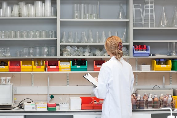 Serious female scientist writing on her clipboard in a laboratory